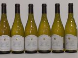 six bottles of white wine lined up in a row on a table