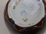 a close up of a brown and white vase with a tag on it