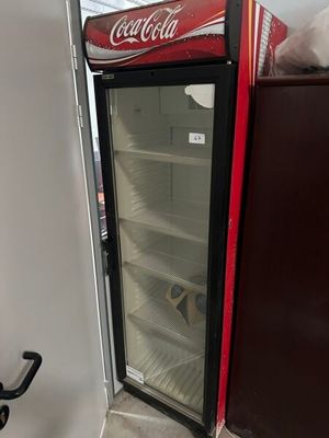 a coca cola cooler sitting in the corner of a room