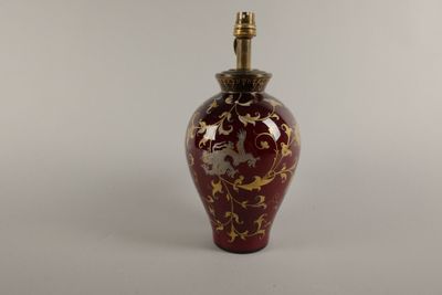 un vase rouge et doré surmonté d'une lampe