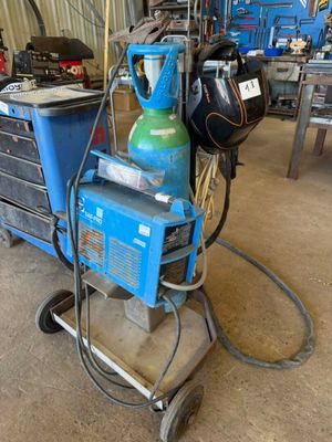 un chariot bleu sur lequel se trouve une bouteille verte, dans un garage