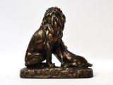 bronze statue of a lion sitting on a rock on a white background