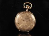 an image of a gold pocket watch on a black surface