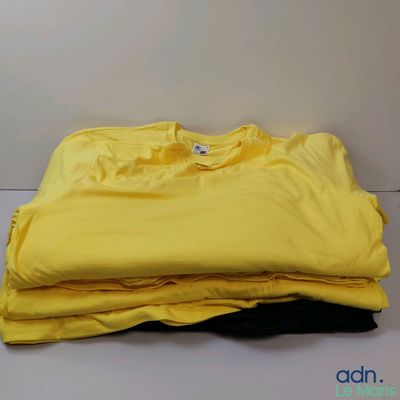 trois t-shirts jaunes empilés les uns sur les autres sur une table