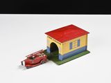 un camion de pompiers miniature et une petite maison posés sur une surface blanche