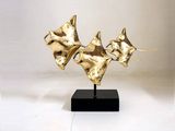 a gold sculpture of a group of fish on a black stand