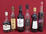 bottles of alcohol lined up on a table with a red background