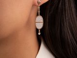 a close up of a woman wearing a white shirt and earrings