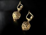 a pair of gold earrings on a black background