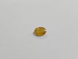 a yellow sapphire stone on a white surface