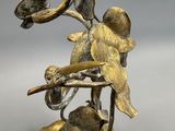 bronze figurine of a bird on a branch with a flower in its beak