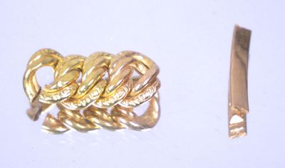 une bague en or et un couteau posés sur une surface blanche
