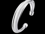 un gros plan d'un bracelet manchette en argent sur fond noir