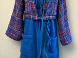 manteau violet et bleu à franges, posé sur un présentoir pour mannequin