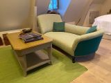 un canapé et un fauteuil dans une pièce où l'on aperçoit un lit à l'arrière-plan