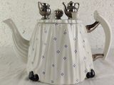 a white teapot with blue flowers on it on a table