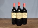 three bottles of red wine sitting on top of a wooden table
