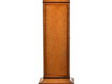 une grande horloge en bois posée sur un socle, avec un cadran blanc