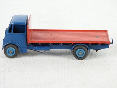 un camion jouet bleu et rouge posé sur une surface blanche
