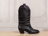 a pair of black cowboy boots sitting on top of a wooden table