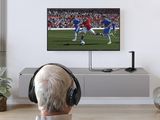 a man sitting on a couch watching a soccer game on tv