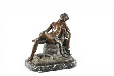 statue en bronze représentant un homme assis sur un rocher avec un chien