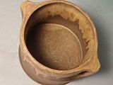 a brown bowl sitting on a table next to a cup