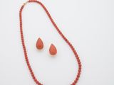 une photo d'un ensemble composé d'un collier et de boucles d'oreilles posé sur une surface blanche