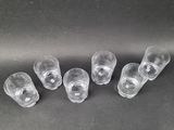 six clear glass cups are lined up on a black surface