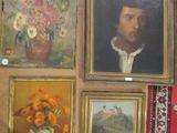 de nombreux tableaux accrochés au mur d'une pièce où se trouve un vase de fleurs