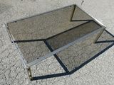 une table en verre avec un piètement en métal, posée à même le sol