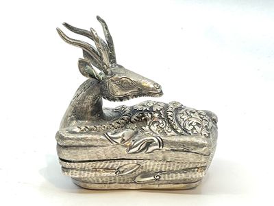 boîte plaquée argent sur laquelle est représenté un cerf, posée sur un fond blanc