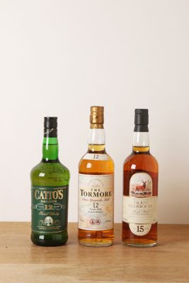 trois bouteilles d'alcools différents posées sur une table en bois