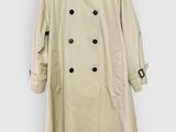 a beige trench coat hanging on a white wall