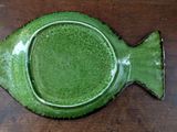 a green fish shaped dish sitting on a wooden table