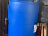 un fût bleu posé sur une palette à côté d'un téléviseur