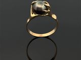 une bague en or sertie d'une perle noire sur un fond noir
