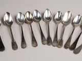 six silver spoons are arranged in a row on a white surface