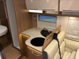 a small kitchen with a sink and a bed in the back