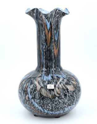 un vase noir et bleu posé sur une surface blanche