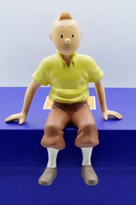 une figurine représentant un homme assis sur une boîte bleue