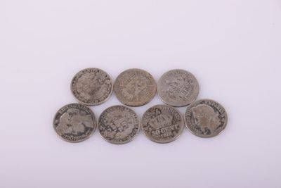 six pièces de monnaie britanniques différentes empilées les unes sur les autres sur une surface blanche