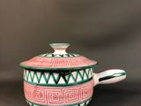 a pink and green pot with a lid sitting on top of a table