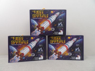 trois boîtes contenant des jouets sur le thème de l'espace sont posées sur une surface blanche