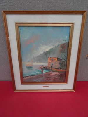 framed oil painting of a boat on the beach by a red tablecloth
