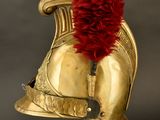 gold helmet with a red feather on top of it on a stand