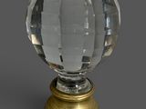 une boule de verre avec un socle doré sur fond gris
