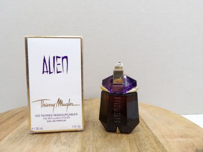 an alien perfume bottle sitting on top of a wooden table next to a box