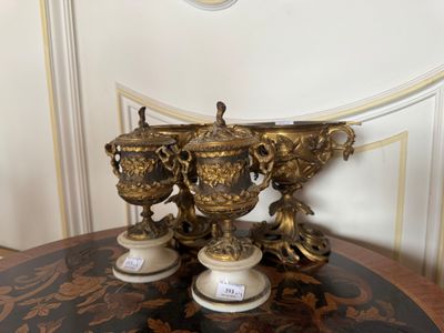 trois vases posés sur une table, avec une horloge en arrière-plan