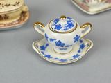a small blue and white tea pot and saucer on a table